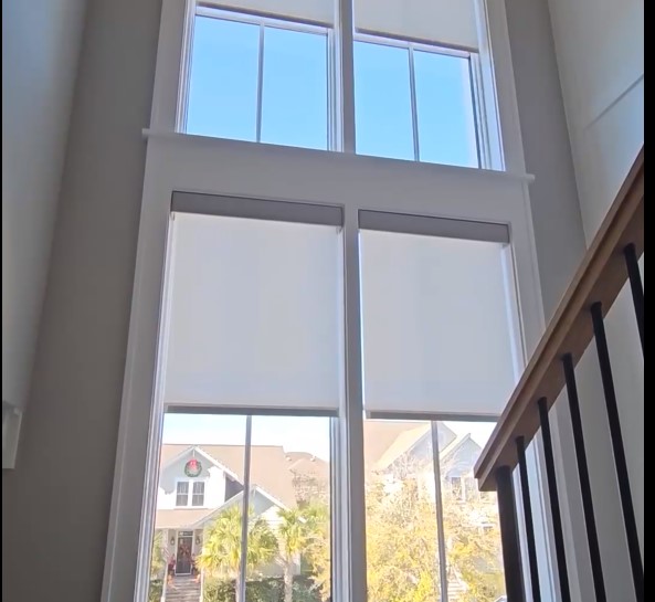 sheer shades rolling up on windows overlooking staircase using motorization